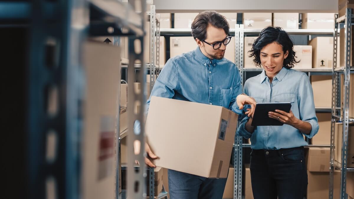 Dos operadores de logística revisando un paquete a ser enviado