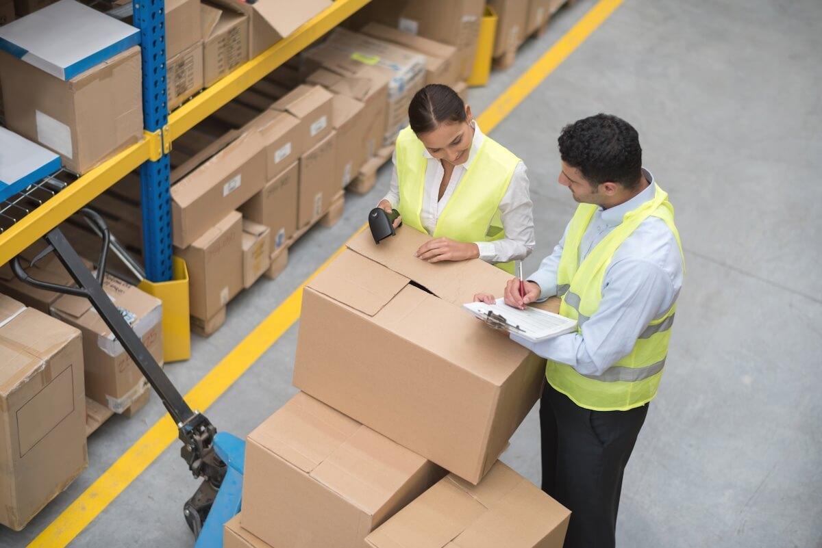 Operadores logísticos en depósito revisando pedidos de clientes